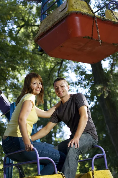 Cheerful young couple on the carousel — Stock Photo, Image