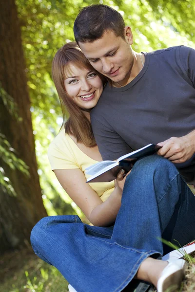 Casal lendo um livro no parque — Fotografia de Stock