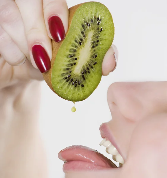 Mulher espremendo kiwi na boca — Fotografia de Stock