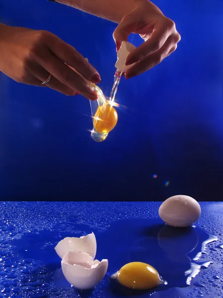 Разбитое яйцо над синим — стоковое фото