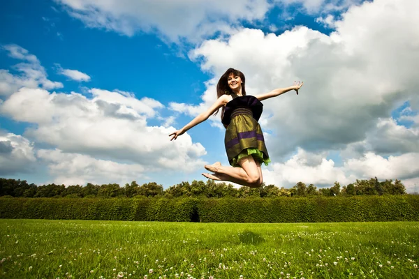 Hübsches lächelndes Mädchen springt auf Grün — Stockfoto