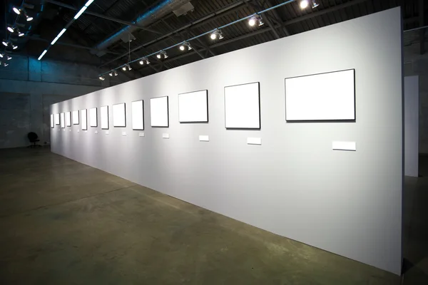 Bílá zeď s mnoha prázdné rámečky — Stock fotografie