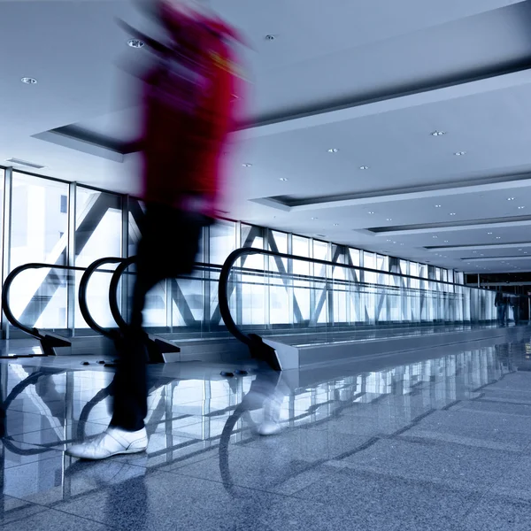Osoby poruszają się w szary korytarz z escala — Zdjęcie stockowe