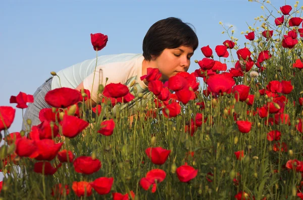 Handsome girl smells poppies — Stock Photo, Image