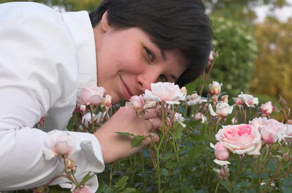 Mulher cheira a rosas — Fotografia de Stock