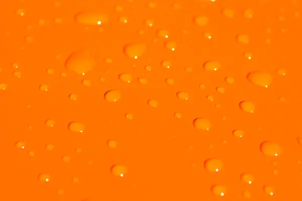 Waterdruppels op oranje metalen achtergrond — Stockfoto