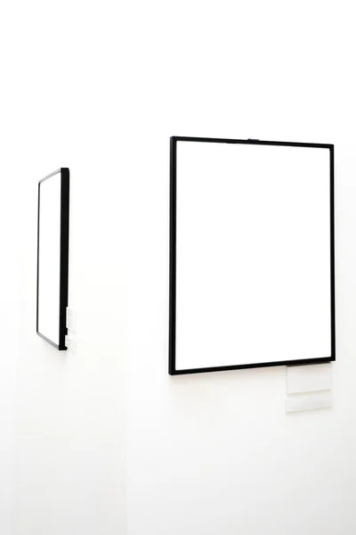 Dva prázdné rámečky na bílé zdi — Stock fotografie