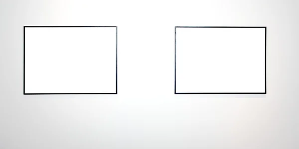 Dva prázdné rámečky na bílé zdi — Stock fotografie