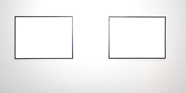 Two empty frames on white wall in museum