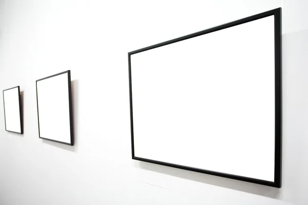 Three empty frames on white wall — Stock Photo, Image