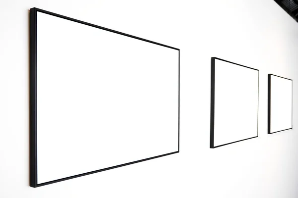 Tři prázdné rámečky na bílé zdi — Stock fotografie