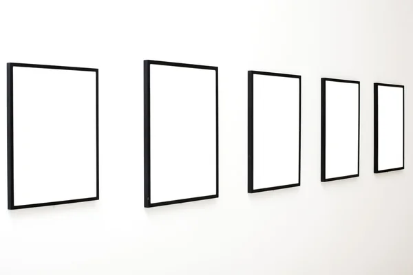 Cinq cadres vides sur mur blanc — Photo