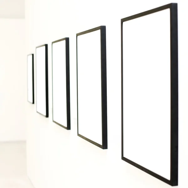 Cinco marcos vacíos en la pared blanca — Foto de Stock