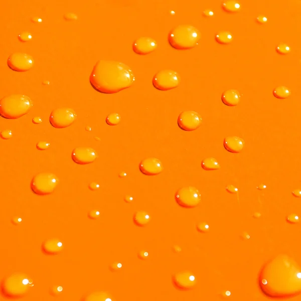 Капли воды на фоне оранжевого металла — стоковое фото