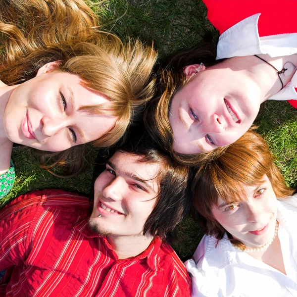Vier tiener lag op gras — Stockfoto