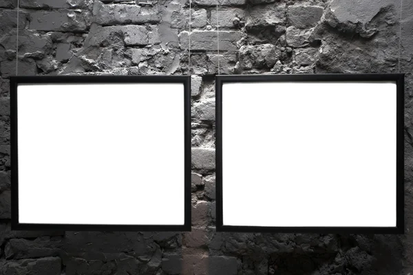 Two empty frames on brick wall