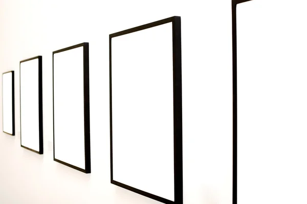 Cinco marcos vacíos en la pared blanca —  Fotos de Stock