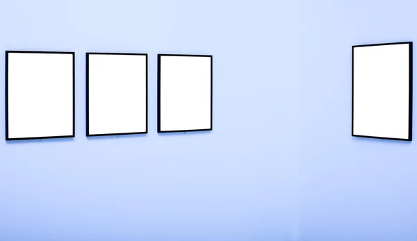 Čtyři bílé prázdné rámečky na modré zdi — Stock fotografie