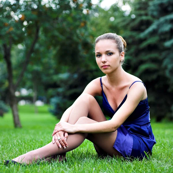 Tiener meisje in blauwe zitten op gras — Stockfoto