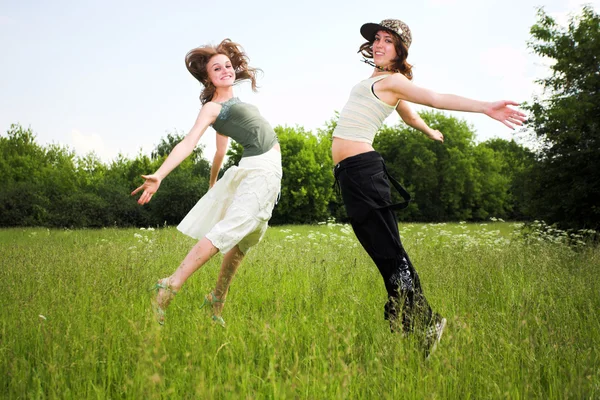 Två hoppande flickor på blå himmel — Stockfoto
