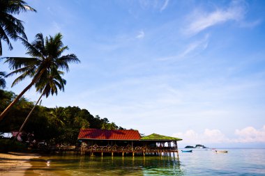 Bungalows on water and palms clipart