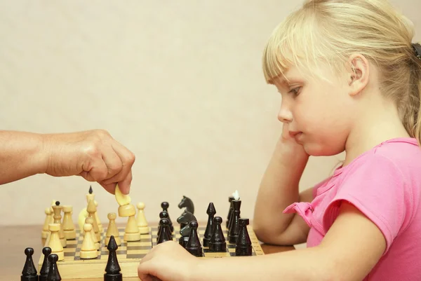 Девушка в розовом платье играет в шахматы — стоковое фото