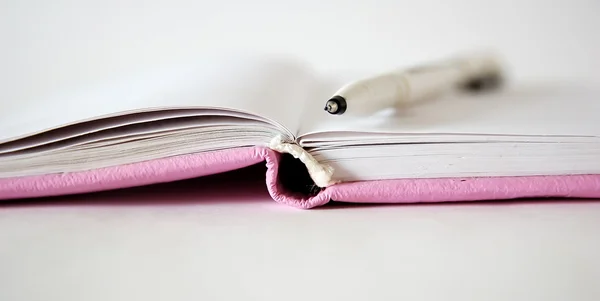 Розовый блокнот и ручка — стоковое фото