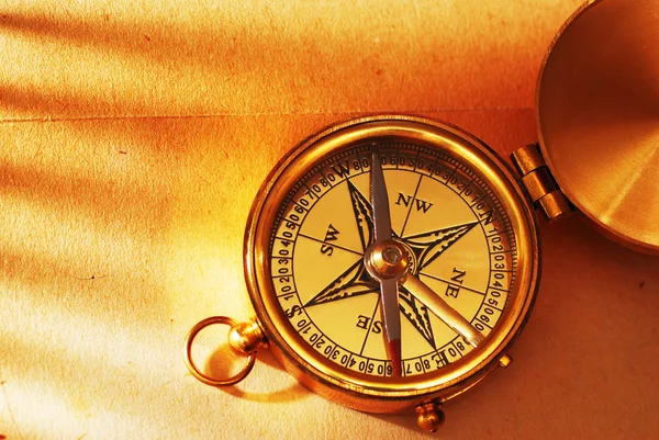 Античный латунный компас над старой спинкой — стоковое фото