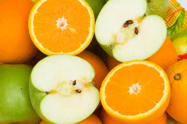 Close up de laranjas e maçãs cortadas pela metade — Fotografia de Stock