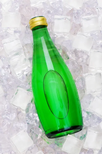 Botella verde de agua en cubos de hielo —  Fotos de Stock