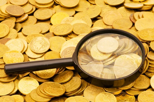 Magnifying glass and gold coins — Stock Photo, Image