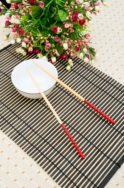 Eetstokjes en kom op de bamboe mat — Stockfoto