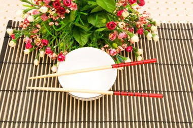 Chopsticks and bowl on the bamboo mat clipart