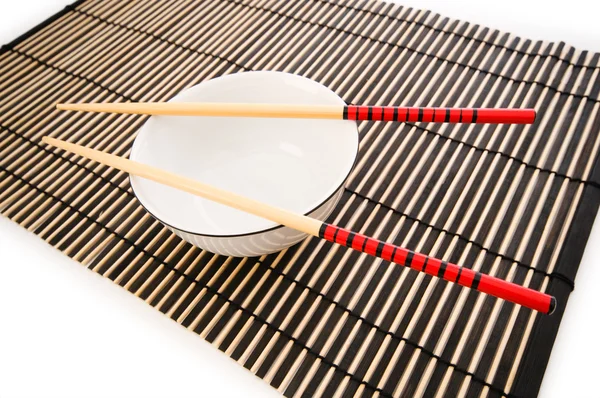 Ciotola e bacchette sul tappetino di bambù — Foto Stock