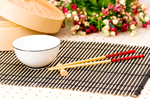 Palillos y tazón en la estera de bambú — Foto de Stock