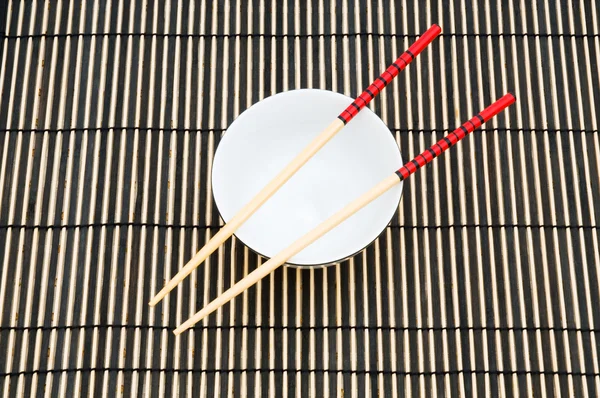Essstäbchen und Schale auf der Bambusmatte — Stockfoto