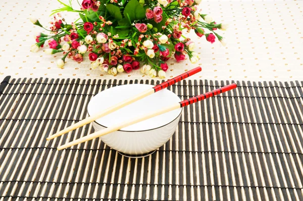 Палочки и миска для еды на бамбуковом коврике — стоковое фото