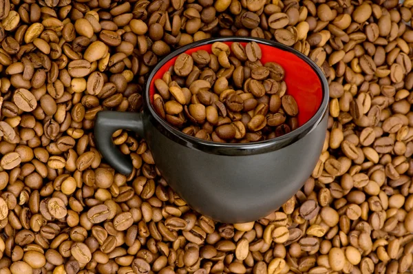 Svart kopp på bakgrunden kaffe — Stockfoto