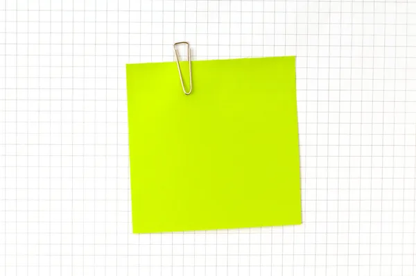Зеленая нота с зажимом на бумаге — стоковое фото