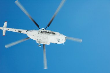 Flying helicopter against blue sky clipart