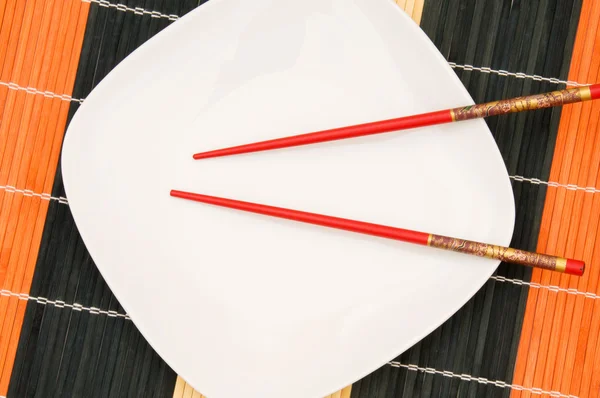 White plate with red chopsticks — Stock Photo, Image