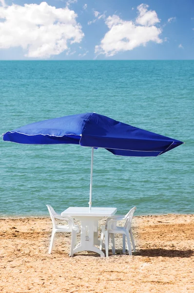 Asztal, székek és napernyő a strandon — Stock Fotó