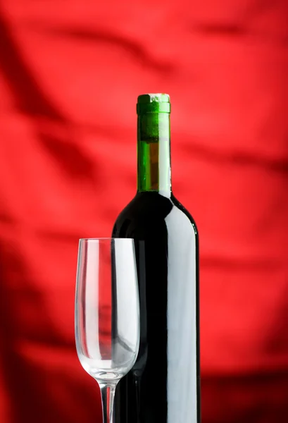 Wine glass and bottle against red — Stock Photo, Image