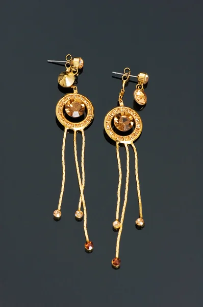 Pair of golden earrings on black — Stock Photo, Image
