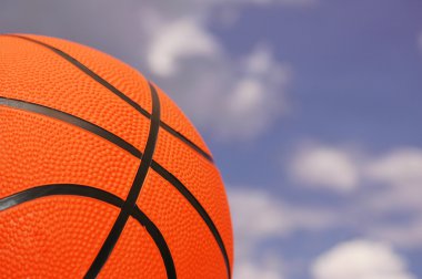Orange basketball against cloudy sky clipart
