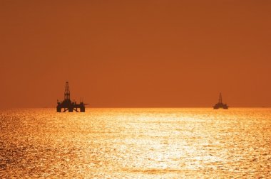 gün batımı sırasında iki offshore petrol kuyuları