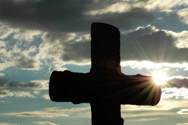 Silhouette of a cross against sun clipart