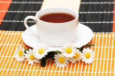 Cup of tea with herbs and daisies clipart