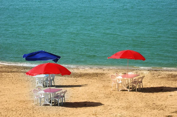 Three tables with parasols at beach — Stock Photo, Image