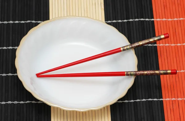 Белая тарелка и палочки для еды — стоковое фото